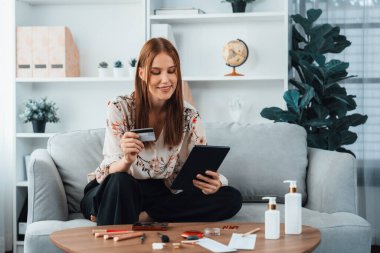 Genç mutlu kadın internetten alışveriş yaparak ürün satın alırken aynı zamanda internet üzerinden online ödeme sistemi ile çevrimiçi mağaza platformundan en yüksek siber güvenlik tarafından korunan ürünler sipariş ediyor.