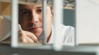 Kafkasyalı mimar mühendisinin yakın çekimi ev inşaatını denetlemek ve bina malzemelerini kontrol etmek. Proje yöneticisi modele dikkatlice bakarken kalemi işaret ediyor. Yönlendirici.