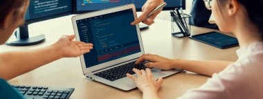Bilgisayar ekranında program kodu gösterilirken iki akıllı kooperatif bilgisayar mühendisi program kodunu çözmek için takım çalışması yapıyor. Laptop, web geliştirme, programcı, Java betiği. Filizlenen.