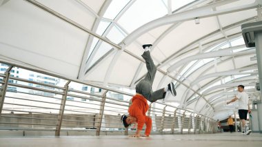 Hipster 'ın kulaklık taktığı ve enerjik adımlar atarken hip hop dinlediği bir sahne. Break dansçı dondurucu poz veriyor. Sokak dansı. Modern yaşam tarzı. Açık hava sporu 2024. Yumuşak bir şekilde..