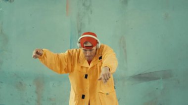 Beyaz hipster sokak, şehir merkezinde ayak sesleri gösteriyor ya da pratik yapıyor. Break dansçı, kulaklıktan müzik dinlerken hip-hop müziğine adım atıyor. Açık hava sporu 2024. Gri arka plan. hiphop.