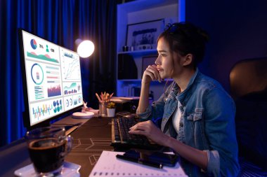 Gülümseyen genç, güzel Asyalı yaratıcı satış hedefi raporunun kar tablosuna bakıyor ve notlar üzerine notlar yazarak neon ışığı gecesinde yeni bir strateji pazarı projesine yatırım yapmayı planlıyor. Taktik.