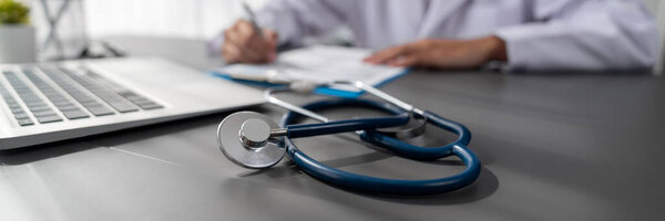 Фокус-стетоскоп на кабинете врача с размытым фоном просмотрения врачом медицинского заключения и диагностики заболеваний для эффективного плана лечения пациента. Неотвратимость