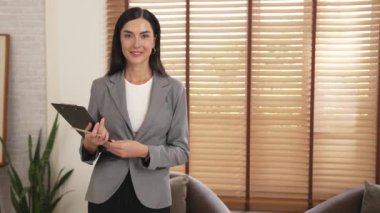 Mutlu ve gülümseyen kadın psikolog psikiyatri ofisinde ya da terapi odasında pano tutuyor. Arkadaş canlısı ve profesyonel ruh sağlığı danışmanı ya da terapisti. Blithe