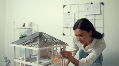 Genç, güzel ve zeki mühendisin yakın çekimleri modern ofiste duvarında taslak olan kalem kullanarak ev modelini ölçmeye odaklanıyor. Yaratıcı yaşam ve tasarım konsepti. Tertemiz..