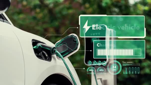 自然公園内のクリーンエネルギー充電ステーションから未来的なスマートEv充電器によってデジタルバッテリーステータスホログラムディスプレイで電気自動車の充電 未来的な環境に優しいEv車 Peruse — ストック動画