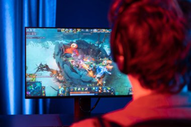 Savaş arenasında çoklu oyunlar takımıyla Moba 'da savaşan genç oyun flamasının sunucu kanalı, neon dijital ışık modern odasındaki arka görüntü ile bilgisayar monitöründe kulaklık takıyor. Toplayıcı.