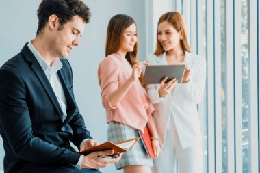 Kitap okuyan ve iş yerinde iş arkadaşları ve arkadaşlarıyla çalışan genç ve yakışıklı bir işadamı. Kurumsal iş adamları grubu. uds