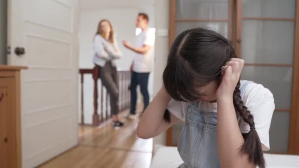 ストレスを受け 不幸な若い少女が角を曲がり 彼女の耳が彼女の親が背景で主張する音を遮断するのを隠している 自宅での家庭内暴力と外傷的な子供時代はうつ病に発展する ファスティオディオス — ストック動画