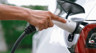 Modern çevre dostu adam EV şarj istasyonundan elektrikli aracı şarj ediyor. EV araba teknolojisi ev sakinleri için gelecekte çevresel sürdürülebilirlik için kullanılıyor. Eşzamanlama