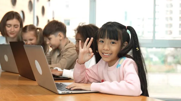スマートなアジアの少女は ノートパソコンで大丈夫か 大丈夫か カメラを見ています Stemテクノロジークラスでコンピュータを使用して 多様な幸せな子供コーディングまたはプログラミングエンジニアリングコードまたはプロンプト エラー — ストック写真