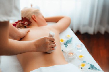 Sıcak bitkisel top spa masaj vücut tedavisi, masör kadın vücuduna nazikçe şifalı bitki torbası bastırıyor. Aromaterapi dinlenme sükuneti ve sükuneti kaplıca salonundaki atmosferi aydınlatıyor. Sessiz.