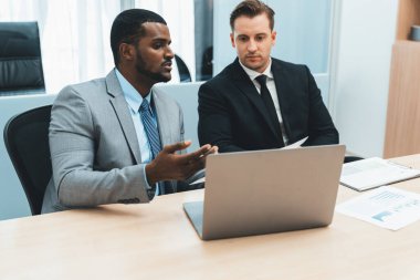 Afrikalı erkek lider stratejiyi açıklarken profesyonel proje yöneticisine çözümünü dizüstü bilgisayar kullanarak belgeye işaret ederek gösteriyor. Yetenekli iş adamlarının beyin fırtınası fikri. İş toplantısı. Süslü.
