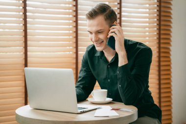 Mutlu iş adamı ya da satıcı online iş yapıyor, uzaktan kumandayla çalışıyor ve evdeki satışlar için telefon görüşmesi yapıyor. Telesyaller ve iletişim ile modern iş. Açılıyor