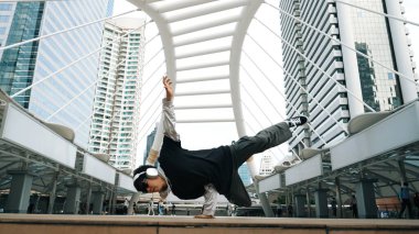 Genç Asyalı hippi şehir merkezinde insanların etrafında ayak izlerini gösteriyor. Şık bir sokak dansçısı B-boy ya da serbest dans eder. Açık hava sporu 2024. Break dans. Yumuşak bir şekilde..