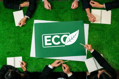 Yeşil çimen masasında panoramik ECO sembolü ve daha sürdürülebilir bir dünya için alternatif enerji kullanımını kurumsal sosyal sorumluluk olarak planlayan iş adamları. Antika