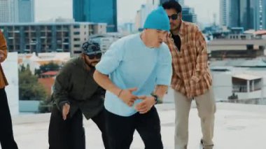 Çatıda çok kültürlü arkadaşlar varken profesyonel İspanyol break dansçısı B boy dansı. Genç modern dans grubu hip hop hareketi yapıyor. Tarz, moda, aksiyon. Açık hava sporu 2024 hiphop..