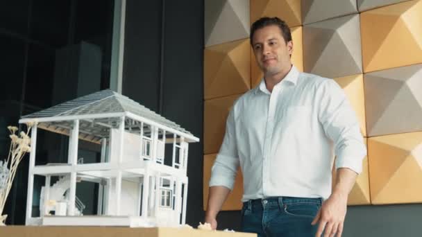 专业的 自信的建筑师工程师微笑着看着相机 手挽手站在那里 把房子模型放在桌子上 职业商人交叉臂 设计理念 机械手 — 图库视频影像