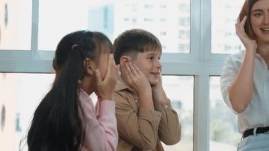 Çeşitli öğrenciler öğretmenle oynarken vücut organlarını öğreniyorlar. Çok kültürlü bir öğrenci, STEM fen dersinde kulağına dokunurken bakıcı etrafında oturuyor. Yaratıcı aktivite konsepti. Etkinlik.