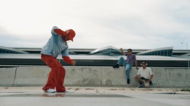 Briçte el sallarken ve el sallarken kulaklık takan mutlu hip hop adamı. Aktif enerjik yenilikçi arkadaş arkada tezahürat yaparken serbest dans ya da ayak sesi yapar. Açık hava müziği 2024. Yumuşak bir şekilde..