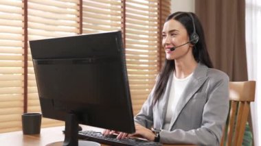 Kadın çağrı merkezi operatörü ya da müşteri hizmetleri çalışanı, müşteriye yardım etmek için kulaklıkla konuşurken çalışma alanı üzerinde çalışıyor. Profesyonel modern iş hizmeti. Blithe