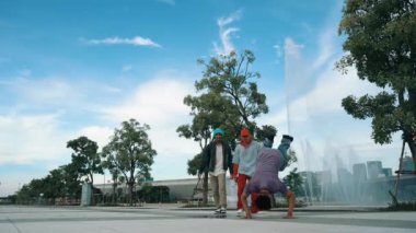 Çekici Asyalı break dansçı B-boy ayak antrenmanı arkadaşı ile. Arkadaş performansı desteklerken profesyonel hipster sokak dansı yapıyor. Serbest stil dansı. Açık hava sporu 2024. Yumuşak bir şekilde..