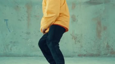 Beyaz hipster sokak, şehir merkezinde ayak sesleri gösteriyor ya da pratik yapıyor. Break dansçı, kulaklıktan müzik dinlerken hip-hop müziğine adım atıyor. Açık hava sporu 2024. Gri arka plan. hiphop.