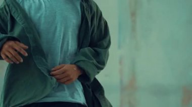 Hippi, şehir caddesinde hip-hop dinlerken kulaklık takıyor. Sokak dansçısı ayak seslerini kulaklıktan müziğe taşıyor. Açık hava sporu 2024. Çimento arka planı. Moda. Aktif stil. hiphop.
