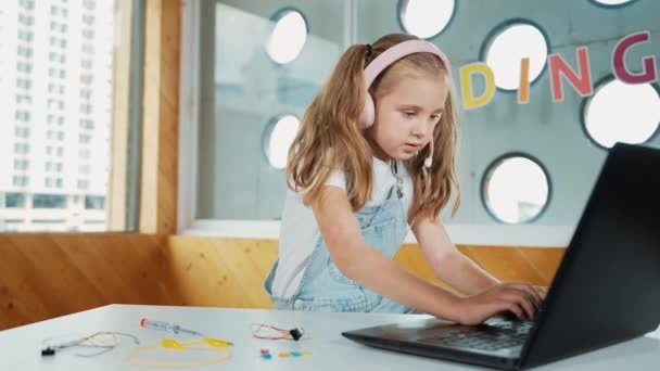 在笔记本电脑上工作或在网上课堂学习的年轻学生 白人女孩在做家庭作业或听音乐的时候在笔记本电脑上打字 戴耳机的小孩创意学习 Erudition — 图库视频影像
