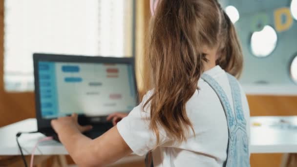 在Stem技术教育中 微笑的女孩展示了系统编程或编码程序 孩子们在工作时戴着耳机 使用笔记本电脑书写代码 转身看相机 Erudition — 图库视频影像