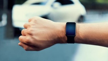 İş adamı, istasyonun otoparkından şarj olurken akıllı ekranda EV akü durumunu kontrol ediyor. EV teknolojisi adaptasyonu için temiz enerjinin gelecekteki yaşam tarzı. İnceleyin