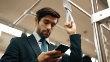 İş adamının elleri trende insanlarla çevriliyken telefona bakarken yakın çekim. Kafkas proje yöneticisi e-postaları kontrol ediyor, arka planı bulanık pazarlama stratejisi planlıyor. Sevinçli..