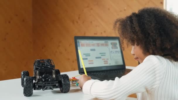 非洲女孩写作或汽车模型结构 而笔记本电脑显示代码 使用笔记本电脑的聪明学生开发程序或学习编程工程提示在Stem课上的应用 — 图库视频影像