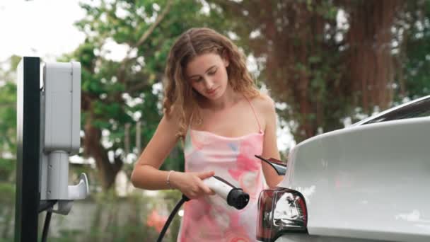 クローズアップ女性は自然公園の駐車場でEv電気自動車バッテリーを充電します 持続可能で環境に優しい旅行のための再充電可能な車のためのクリーンエネルギー技術 ファスティオディオス — ストック動画