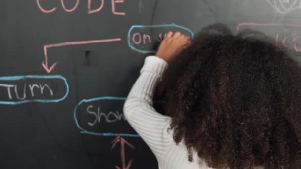 快乐的非洲女孩写黑板 转身对着相机挥手 而站在船上的工程提示或编码 编程系统写在Stem技术教室 Erudition — 图库视频影像