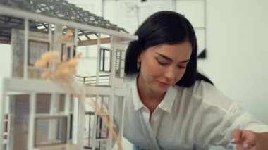 Genç, beyaz, güzel mimar mühendisi ev modelini ev inşaatını teftiş etmek ve sorunu modern ofisteki toplantı masasında çözmek için hata noktasını kontrol etmek üzere çeviriyor. - Yakın çekim. Tertemiz..