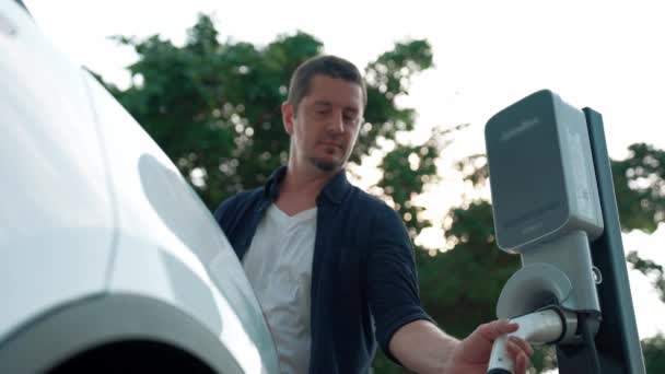 Чоловік Заряджає Батареї Електромобіля Під Час Подорожі Дорозі Автомобіль Природному — стокове відео