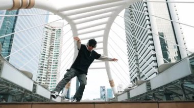 Genç Asyalı hippi şehir merkezinde insanların etrafında ayak izlerini gösteriyor. Şık bir sokak dansçısı B-boy ya da serbest dans eder. Açık hava sporu 2024. Break dans. Yumuşak bir şekilde..