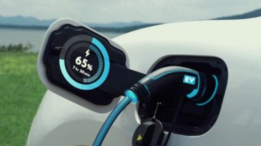 Elektrikli araba şarj istasyonuna bağlanır, EV şarj kablosu ile pili şarj edilir doğası gereği akıllı dijital batarya durum hologramı görüntülenir. Geleceğin yeşil enerji altyapısı. İnceleyin