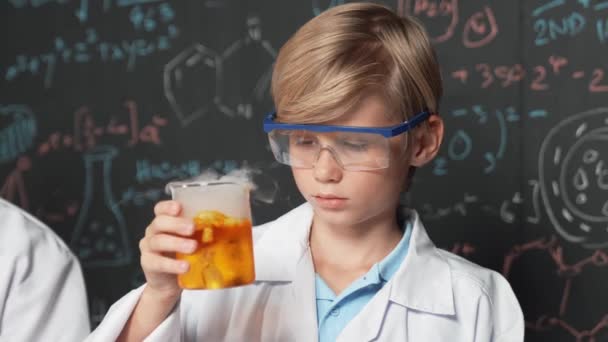 Zbliżenie Inteligentny Chłopiec Przeglądać Mieszaną Substancję Chemiczną Zlewkach Laboratoryjnych Trzymając — Wideo stockowe