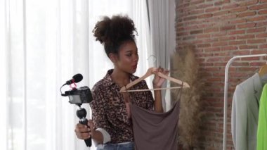 Kadın nüfuzlu kişi canlı yayında video görüntülerini çekiyor. Kıyafetler sosyal medya ya da blog için çok önemli. Stüdyo ışıklandırmalı mutlu genç kız çevrimiçi pazarlama oturumu yayını için..