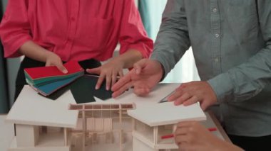 Mimari ekipman kullanarak yavaş çekim ev tasarımcısı bir plan çizerken, iç mimari tasarımcı da müşterilerin talebine göre renk örneklerinden uygun renkler seçiyor. Değiştirilmiş