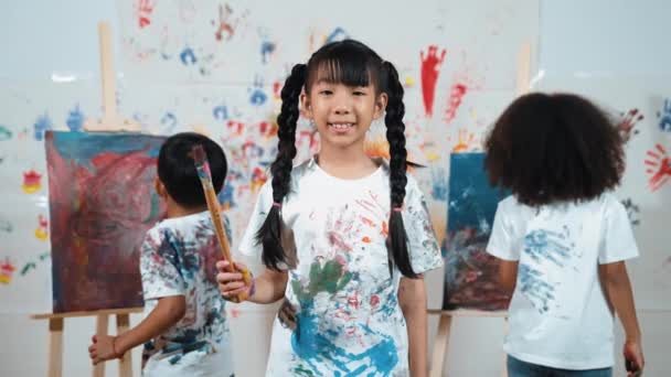 Creatief Schattig Meisje Poseren Camera Terwijl Diverse Kinderen Schilderen Achter — Stockvideo