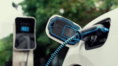 Doğal yeşil araba parkındaki ekolojik temiz enerji şarj istasyonundan gelen fütürist akıllı EV şarj aletinin şarj ettiği elektrikli araba. Alternatif enerji kullanan gelecekçi çevre dostu elektrikli araba. İnceleyin