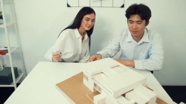 Becerikli mimari mühendisi ekip ölçümü ve ev modeline birlikte çalışırken karar verme ve toplantı odasındaki bina yapısı ve planlarla ilgili tartışmalar. Tertemiz..