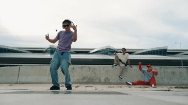 Bir grup Asyalı break dansçı, çok kültürlü arkadaş desteği ve hareketli hip hop müziğiyle sokak dansı yaptılar. Çekici yakışıklı hippi sokak dansında break dansçı. Açık hava sporu 2024. Yumuşak bir şekilde..