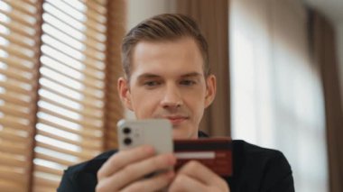 Masada oturan genç adam kredi kartıyla ödeme yapmak için akıllı telefondaki dijital cüzdanı ve uygulamayı kullanıyor. Mobil internet üzerinden alışveriş ve modern alımlar. Düzenle