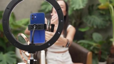 Telefon kamerasıyla odaklan güzel kadın içeriği yaratıcısı ya da arka planda güzellik blogcusu doğal bahçede kozmetik ve güzellik bakımı videosu yapıyor. Blithe