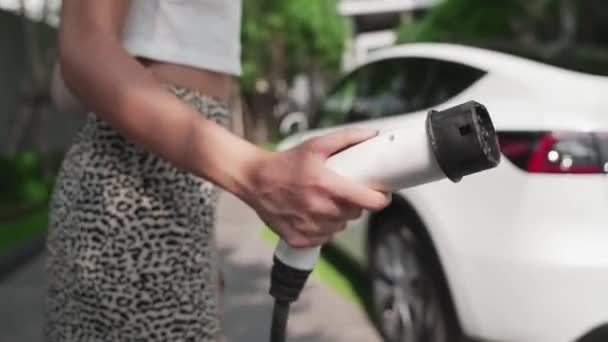 城市住宅区电动汽车充电站慢动作妇女充电电动汽车电池与电动汽车内部可持续绿色可再生能源清洁生活方式的关系 — 图库视频影像