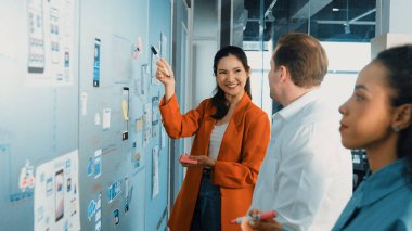 Bir grup iş adamının cam tahtaya yapışkan notlar yapıştırması. Profesyonel iş adamları pazarlama stratejisi geliştirirken cam duvara notlar yapıştırıyor. İş toplantısı. Yönlendirici.